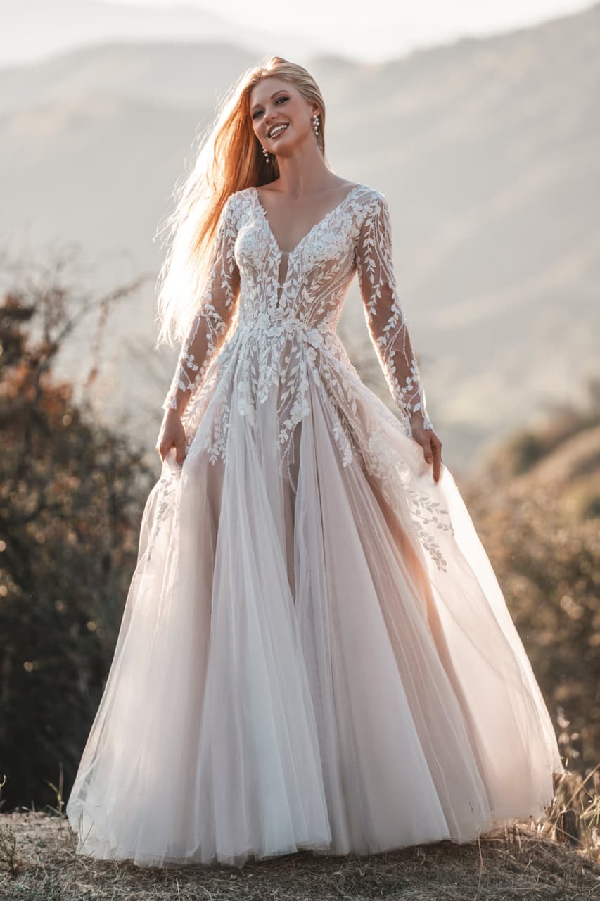 Long sleeve lace wedding dress with V neckline, sheer bodice, and soft A-line tulle skirt outdoors