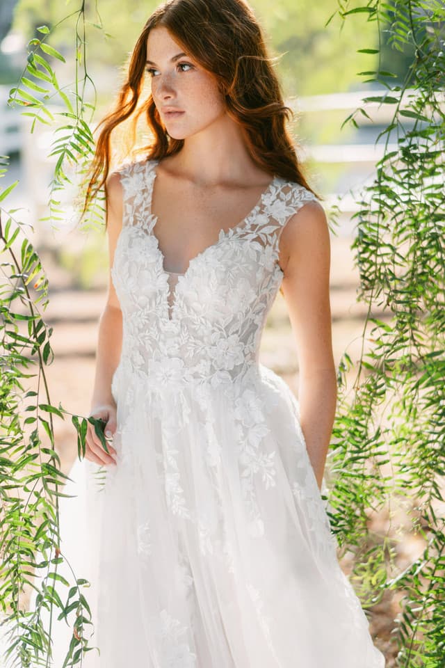 Close-up of lace wedding dress bodice with floral appliqué, V neckline, and soft tulle skirt