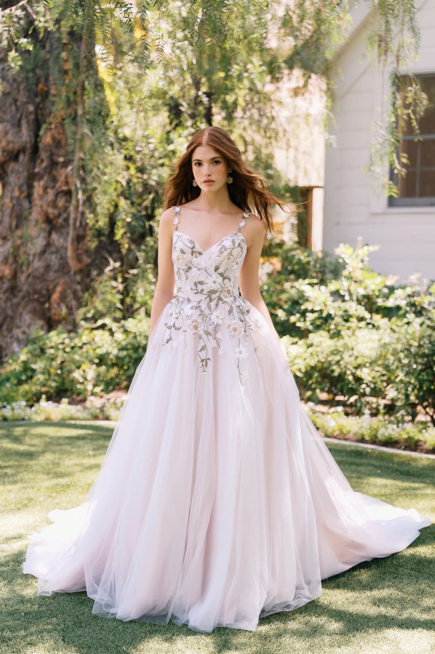 Blush A-line wedding dress with floral embroidery, thin straps, and soft tulle skirt in garden setting