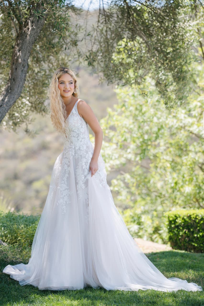A-line wedding dress with floral lace bodice, V neckline, and soft tulle skirt in outdoor setting